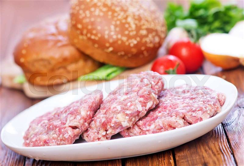 Raw burgers and buns on a table, stock photo