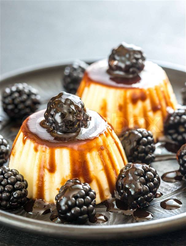 Vanilla puddings with fresh blackberries and berry topping, stock photo