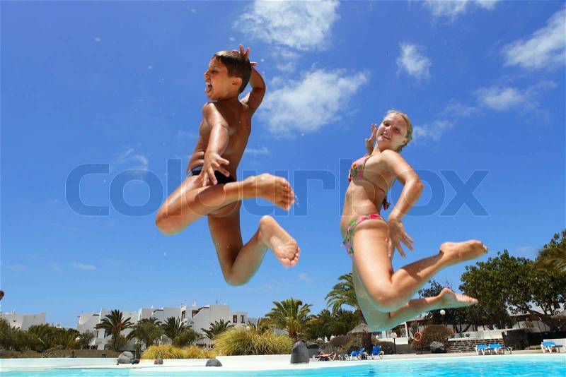 Boy with mum jumping into the pool smiling, stock photo