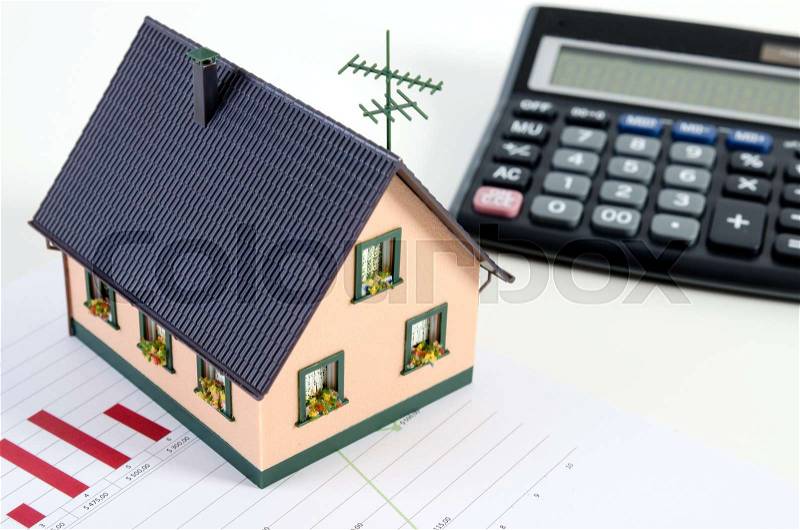 Home finances or saving for a house. House miniature and calculator, stock photo