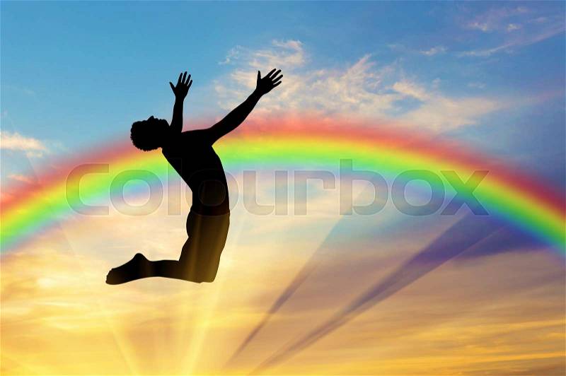 Happiness and success. Happy man jumping on the background of the rainbow in the sky, stock photo