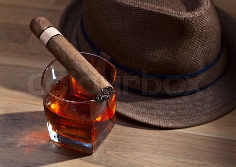 Whiskey with ice and cigar on a old wooden table, stock photo