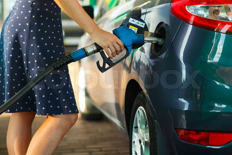 Woman fills petrol into the car at a gas station, stock photo