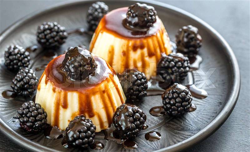 Vanilla puddings with fresh blackberries and berry topping, stock photo