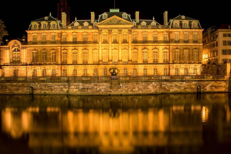 Night photography with the famous Rohan Palace from Strasbourg, France and its reflection in Ill river water, stock photo
