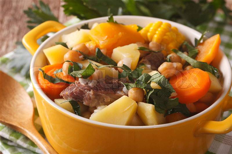 South American cuisine: Puchero soup with chickpeas close-up in a pot on the table. horizontal , stock photo