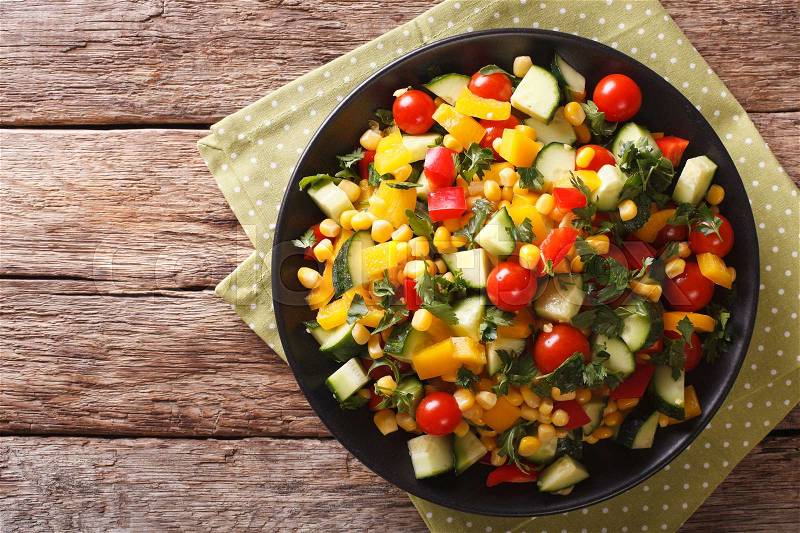 Dietary salad of corn, greens, tomatoes, cucumbers and pepper close-up on the table. Horizontal view from above , stock photo