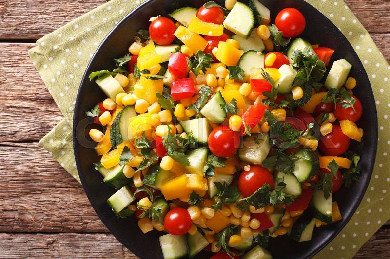 Low calorie salad of corn, tomatoes, cucumbers and pepper close-up on the table. Horizontal view from above , stock photo