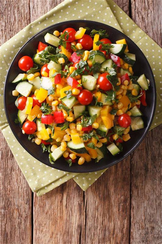 Dietary salad of corn, greens, tomatoes, cucumbers and pepper close-up on the table. vertical view from above\, stock photo