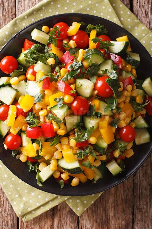 Low calorie salad of corn, tomatoes, cucumbers and pepper close-up on the table. vertical view from above\, stock photo