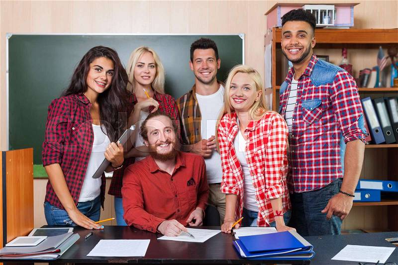 Student High School Group With Professor Sitting At Desk, Smiling Young People University Classroom Over Chalkboard, stock photo