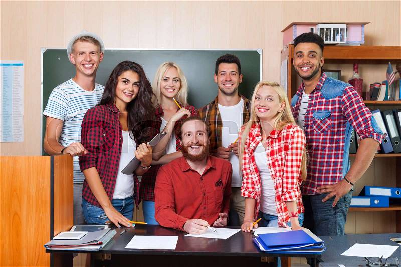 Student High School Group With Professor Sitting At Desk, Smiling Young People University Classroom Over Chalkboard, stock photo