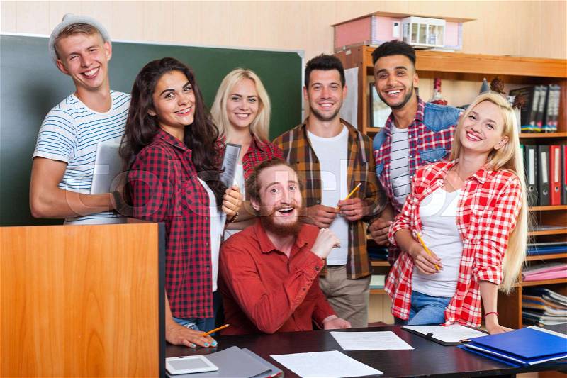 Student High School Group Laughing With Professor Sitting At Desk, Smiling Young People University Classroom Over Chalkboard, stock photo