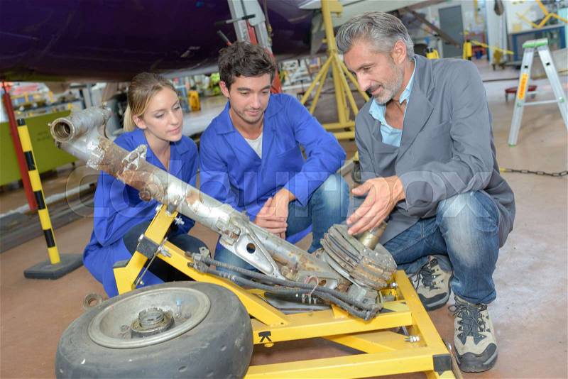 Technicians looking at dismantled aircraft landing gear, stock photo