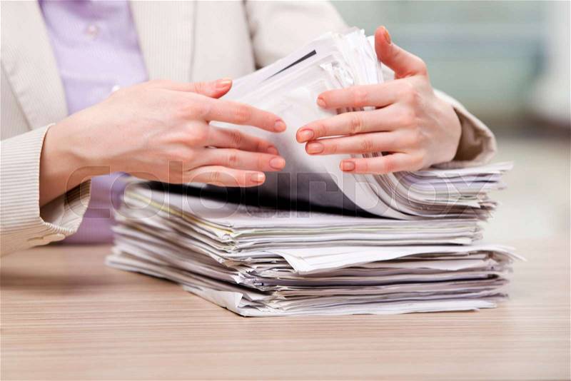 Businesswoman working with stack of papers, stock photo