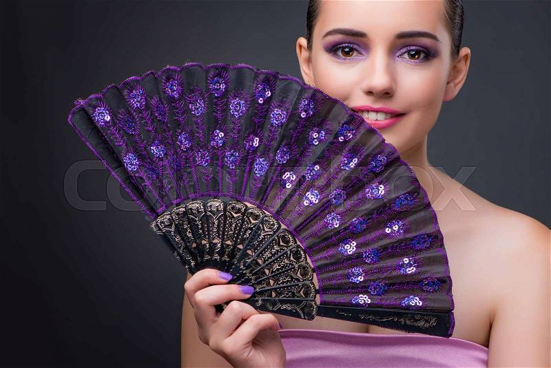 Nice woman with fan against gray background, stock photo