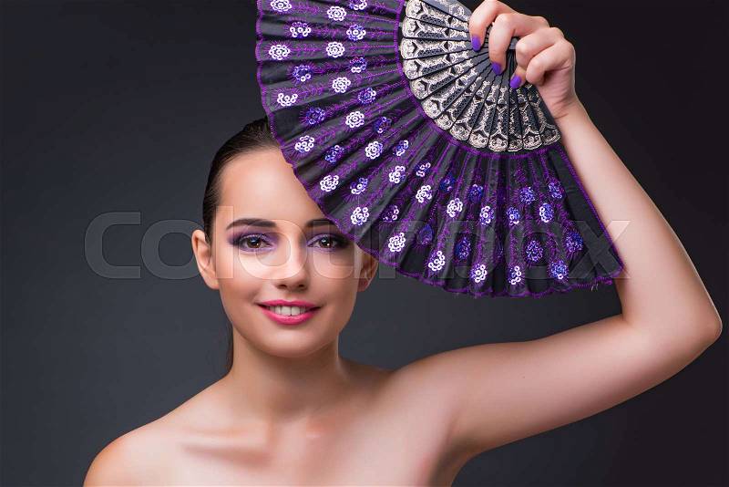 Nice woman with fan against gray background, stock photo