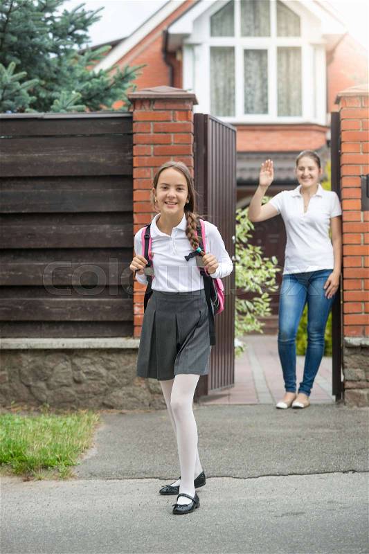 Beautiful smiling girl going out of the house backyard to school, stock photo