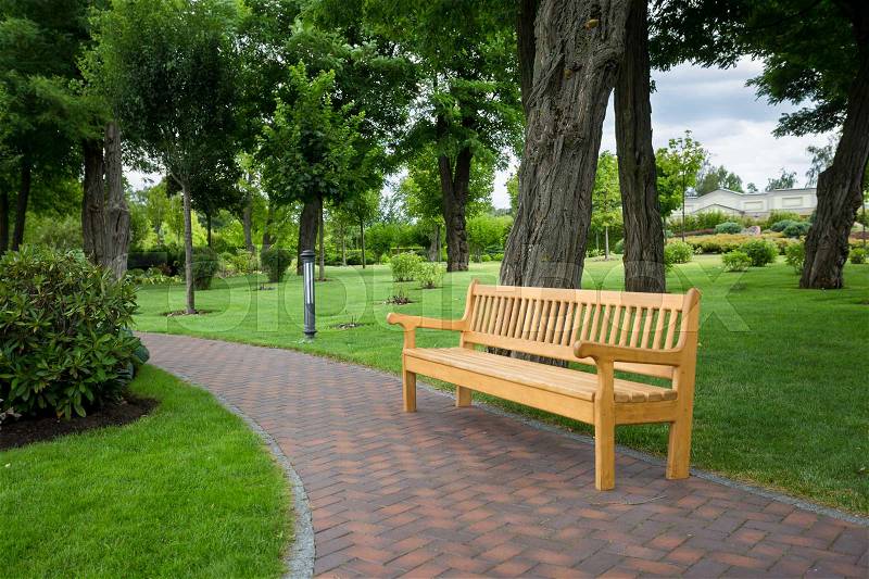 Wooden bench on path at beautiful park, stock photo