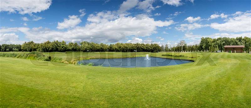 Panorama of golf course with pond in sunny summer day, stock photo