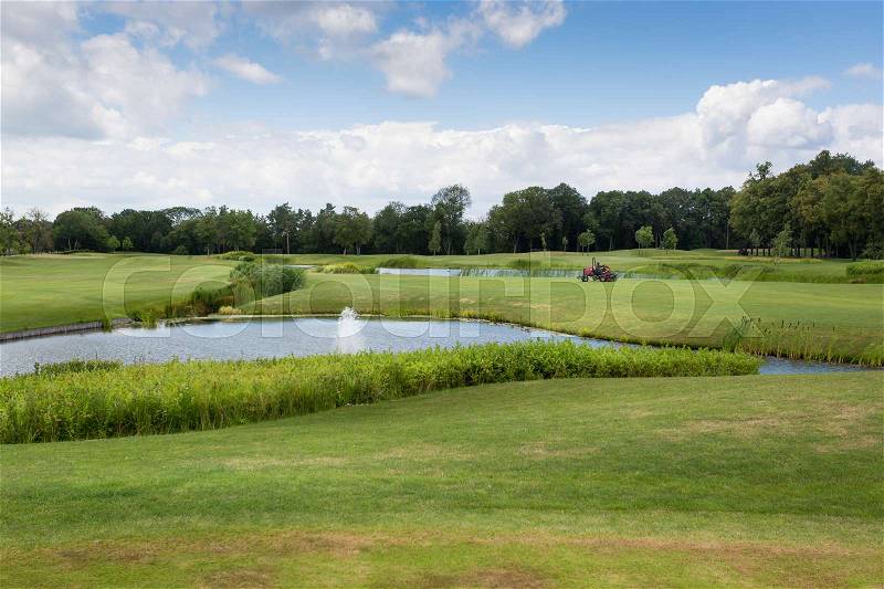 Beautiful view on golf course with perfect green grass and pond, stock photo