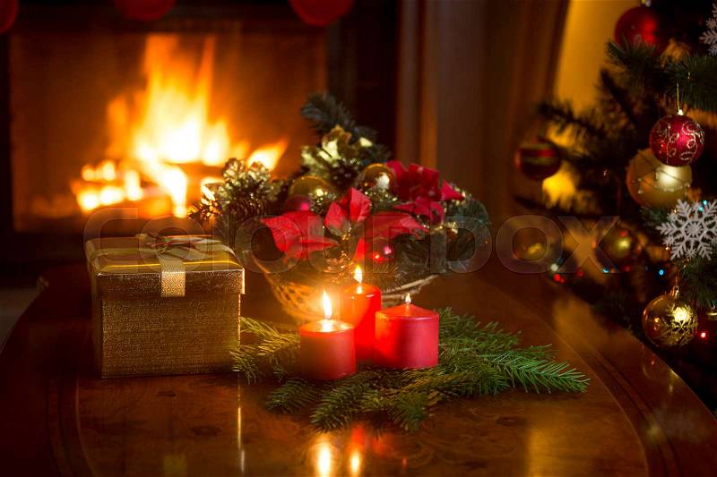 Beautiful Christmas wreath with red candles in living room with burning fireplace, stock photo