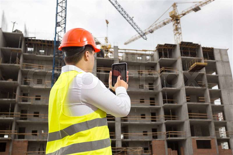 Young engineer on building site with digital tablet, stock photo