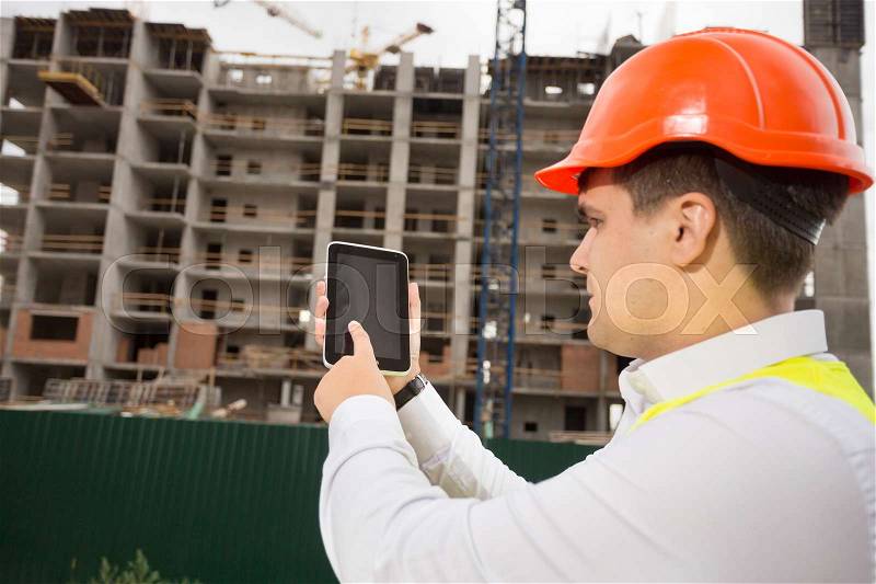 Portrait of young construction engineer using digital tablet on building site, stock photo