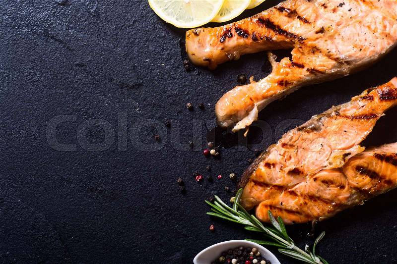Grilled salmon steak on stone with spices, stock photo
