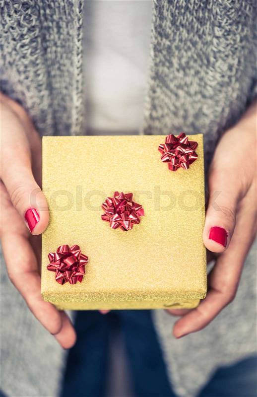 Woman hands hold small golden jewlery gift box for Christmas or New Year, stock photo