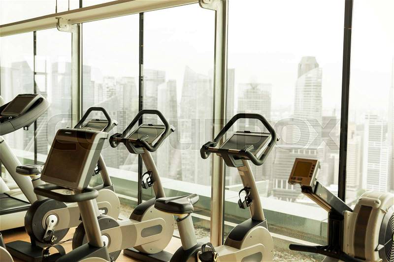 Sport, fitness and health care concept - exercise bikes in city gym, stock photo