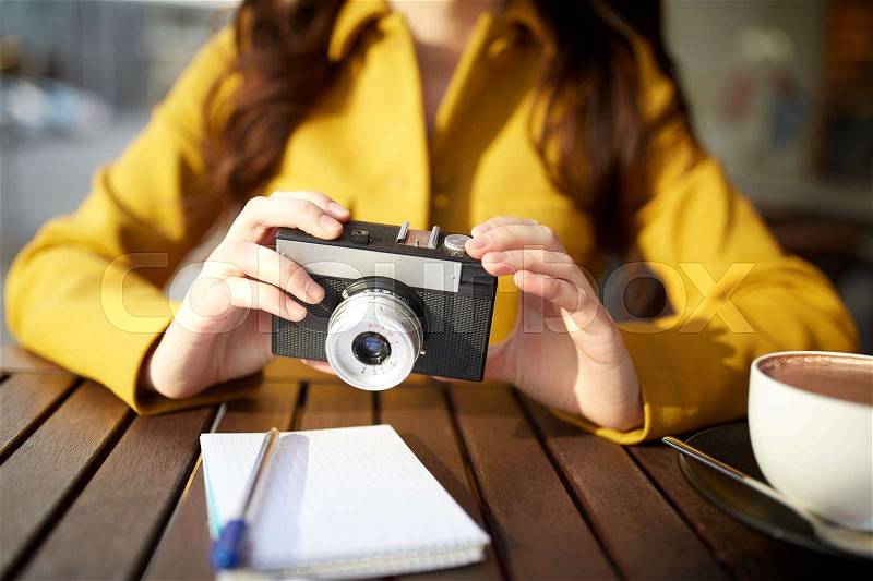 Travel, tourism, photography, leisure and people concept - close up of young tourist woman or teenage girl with film camera and guidebook drinking cocoa at city street cafe terrace, stock photo