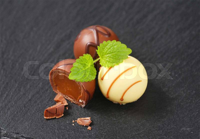 Two and half belgian chocolate pralines on black background, stock photo