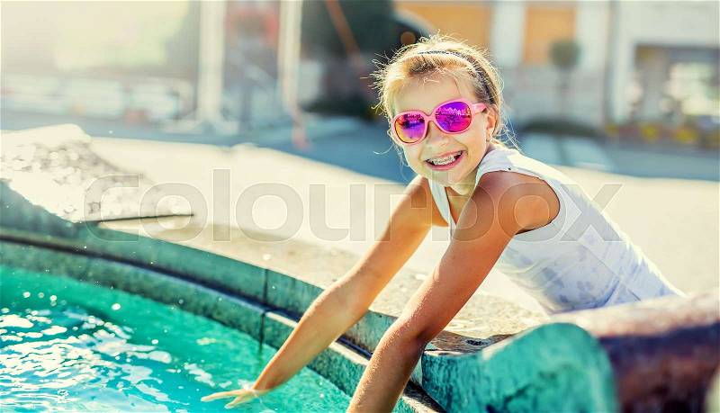 Summer hot day. Cute little girl playing with fountain. Hot weather, stock photo