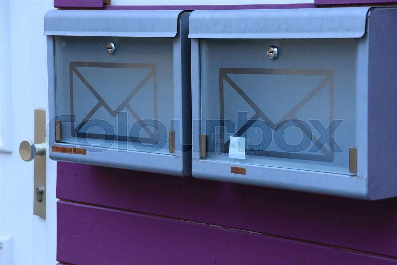Two empty mailboxes on the purple wooden wall in the neighbourhood of the frontdoor of the house in the residential area of the village, stock photo