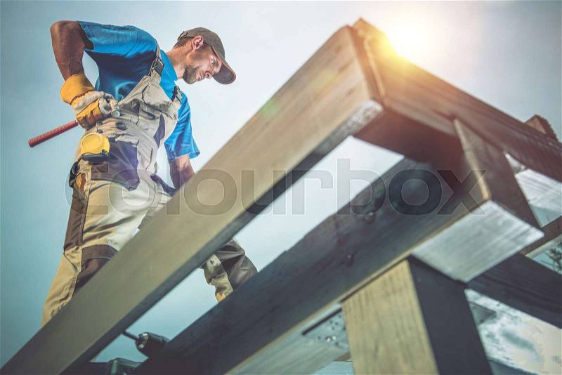 Wood Construction Works. Caucasian Worker on the Wooden Roof Construction, stock photo