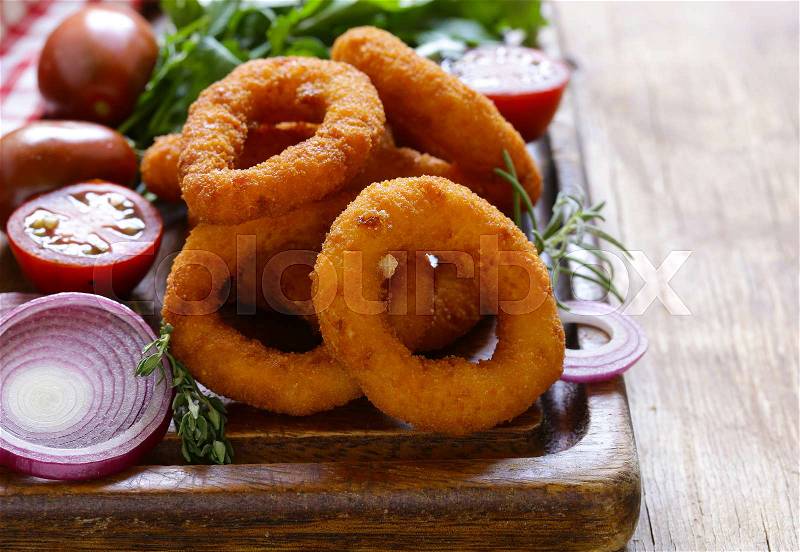 Fried onion rings on a wooden table, fast food, stock photo