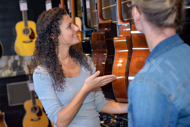 Lady presenting guitars in shop, stock photo