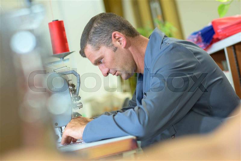 Man using sewing machine, stock photo