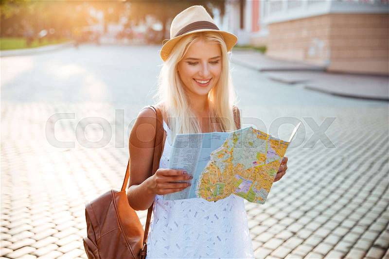 Happy tourist woman on vacation with map visiting city, stock photo