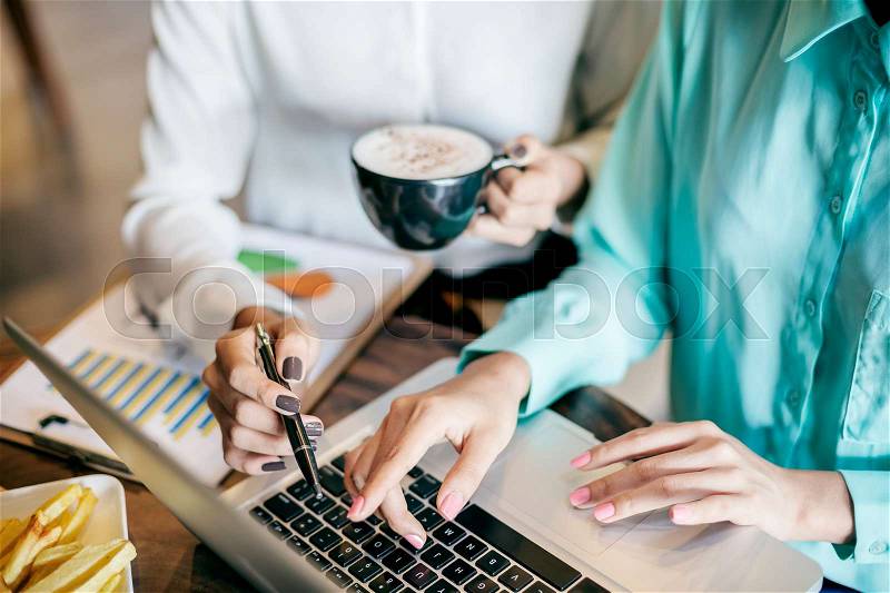 Women discussing work at a coffee shop, stock photo