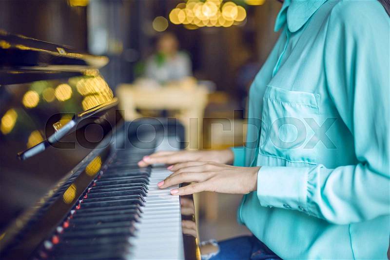 A woman playing piano wearing blue blouse, stock photo