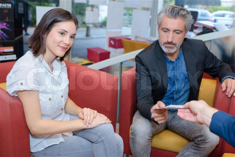 Seated man being passed piece of paper, stock photo
