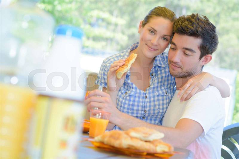 Couple eating breakfast, woman sat on man\'s lap, stock photo