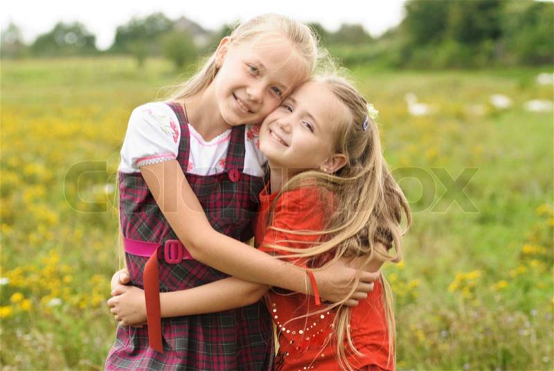 Two sisters hug one another outdoors, happy family, stock photo