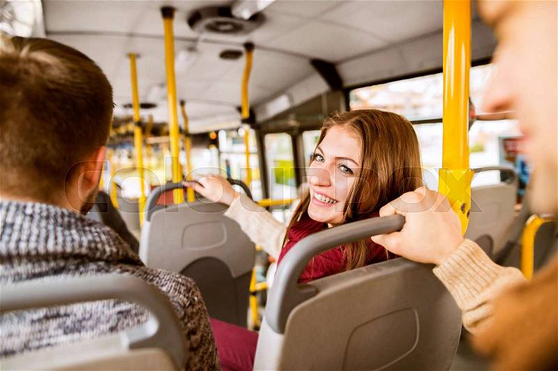 Beautiful young woman traveling by bus with her friends, having fun in town, stock photo