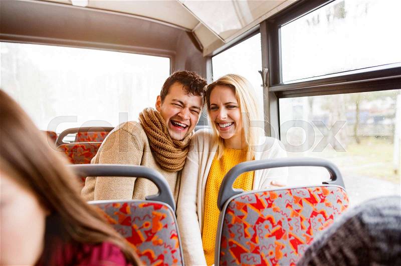 Beautiful young couple traveling by bus, laughing, having fun in town, stock photo