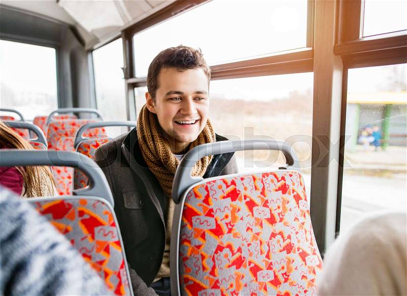 Handsome young man traveling by bus with his friends, having fun in town, stock photo