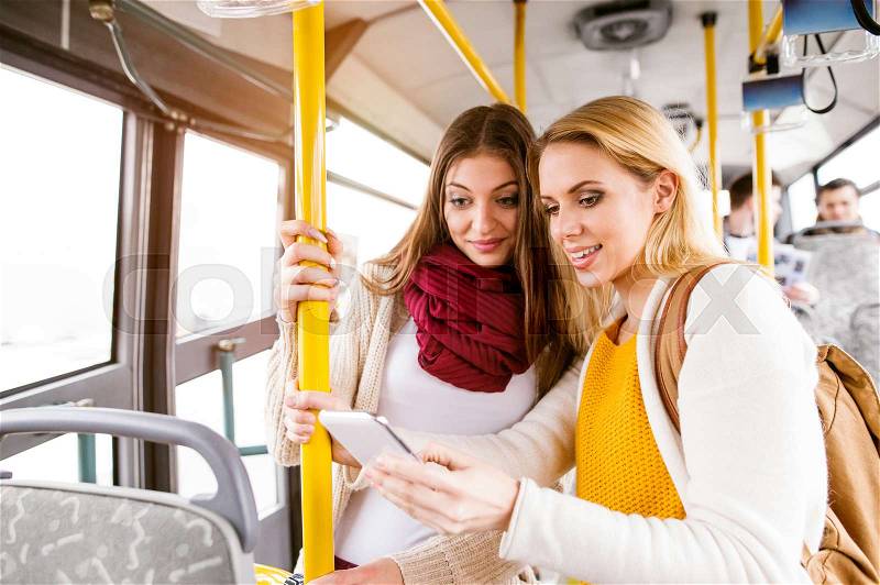 Beautiful young women with smart phone traveling by bus, having fun in town, stock photo