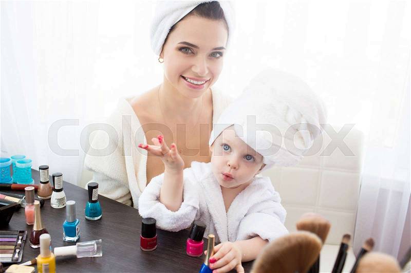 Happy family. Mother and daughter are doing hair, manicures, makeup and having fun. Mother and daughter sitting at dressing table at house, stock photo